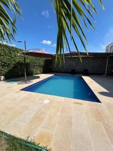 uma piscina com um guarda-sol ao lado de uma casa em Casa moderna con piscina privada Cabo Verde praia em Ricaurte