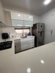 uma cozinha com geladeira de aço inoxidável e armários brancos em Casa moderna con piscina privada Cabo Verde praia em Ricaurte mais 20 fotografias