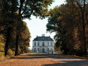 Holiday home Ahorn, 1st floor في Weilerswist: بيت ابيض كبير وامامه اشجار