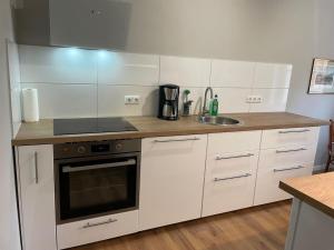 Gable house Ruppin Lake في Karwe: مطبخ بدولاب بيضاء وموقد ومغسلة