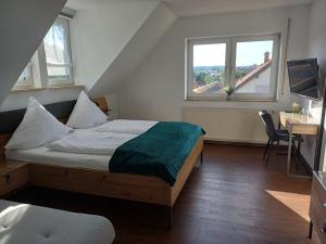 a bedroom with a bed and a desk and two windows at Holiday apartment with 1 bedroom in Herbstein