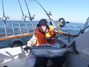 at the Gau family's home in Poggenhof في Charlottendorf: رجل جالس على قارب يمسك سمك