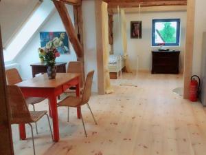 2 with large garden, playground and pool في Sommerstorf: غرفة طعام مع طاولة حمراء وكراسي