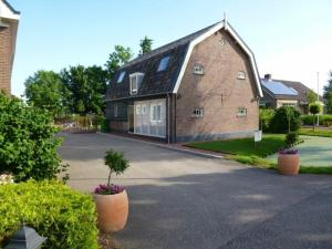 ein großes Backsteinhaus mit einem Baum in der Einfahrt in der Unterkunft De Rijtuigenschuur in Goudriaan
