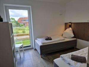 a room with two beds and a large window at Holiday home Ebbe with dog up to 14 people in Schülp