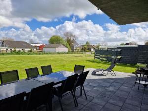 a patio with a table and chairs and a field at Holiday home Ebbe with dog up to 14 people in Schülp