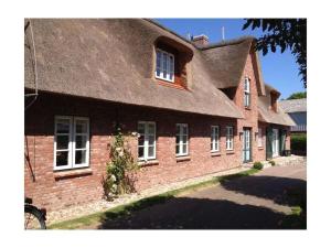 ein großes Backsteingebäude mit einem Strohdach in der Unterkunft Holiday home property 46 in Utersum