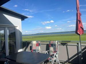 a table and chairs on a balcony with a view of the ocean at Holiday home on Lake Kummerow in Salem