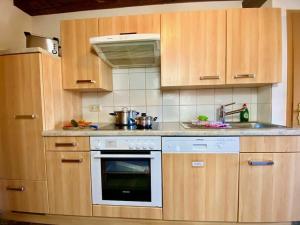 eine Küche mit Holzschränken und einem Herd mit Backofen in der Unterkunft Hoher Göll in Punzenlehen in Engedey