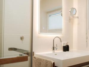 a white bathroom with a sink and a mirror at Alb holiday home Zinnäcker in Trochtelfingen +26 photos