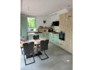 een keuken met groene kasten en een houten tafel en stoelen bij Holiday home Littard in Rheurdt +10 foto's