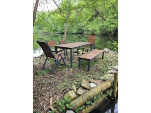 een picknicktafel en stoelen naast een rivier bij Holiday home Littard in Rheurdt
