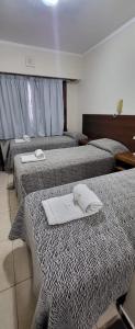 a hotel room with three beds with towels on them at Hotel Bertiami in Mar del Plata