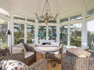 un salón acristalado con sillas, mesa y lámpara de araña en Country House Kühren, en Lütjenburg