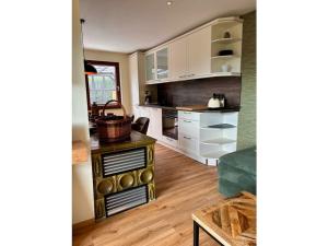 a kitchen with white cabinets and a wooden floor at Holiday home Burgblick in Kranichfeld