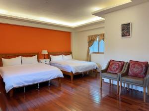 Una habitación de hotel con dos camas y dos sillas. en Jiufen Golden House, en Jiufen