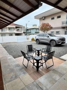 a patio with chairs and a table and a car at Casa Completa litoral SC com 4 qtos com ar condicionado e Aceita Pets in Itapema