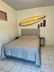 a bedroom with a bed and a surfboard on the wall at Casa Completa litoral SC com 4 qtos com ar condicionado e Aceita Pets in Itapema