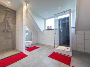 een badkamer met een douche, een toilet en rode matten bij Landzicht in Haps +32 foto's