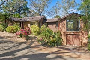 a brick house with a garage and some flowers at Alencon in Blackheath