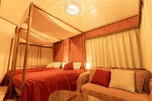 a tent bedroom with two beds and a couch at 那須Bitsは1棟貸で愛犬と過ごせる宿でBBQ無料プロジェクター完備 in Nasu