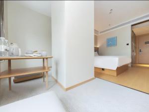a bedroom with a bed and a desk with a table at JI Hotel Hangzhou Alibaba Xixi Park in Hangzhou