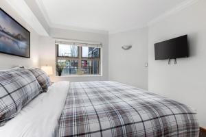 a bedroom with a bed and a flat screen tv at Cozy 1BR, steps from Creekside Gondola by Harmony Whistler Vacations in Whistler