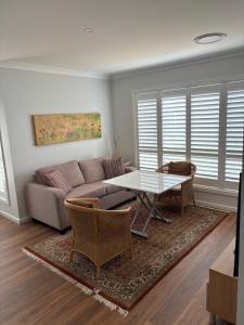 Bundanoon Rochester Guest House في بوندانون: غرفة معيشة بها أريكة وطاولة