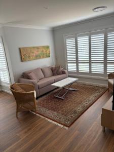 Bundanoon Rochester Guest House في بوندانون: غرفة معيشة بها أريكة وطاولة