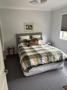 Bundanoon Rochester Guest House في بوندانون: غرفة نوم مع سرير وبطانية منقوشة