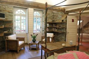 a living room with a stone wall and a table and chairs at Cottage du Manoir de Trégaray in Sixt-sur-Aff