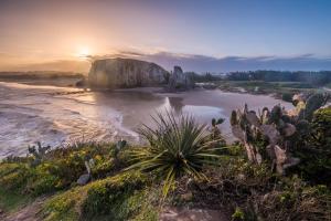 a view of a beach at sunset with a rock formations at Pé na Guarita in Torres