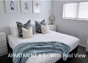 a white bedroom with a bed with pillows at Stay n Play n Russell in Russell