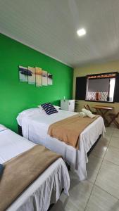 two beds in a room with a green wall at Chalés da Jack in Angra dos Reis