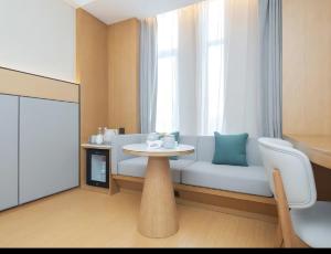 a room with a couch and a table and a window at JI Hotel Hangzhou Alibaba Xixi Park in Hangzhou