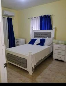 een slaapkamer met een wit bed en blauwe gordijnen bij Tu Casa En Pedernales in Pedernales