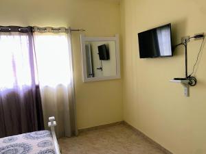 een slaapkamer met een bed, een spiegel en een televisie bij Tu Casa En Pedernales in Pedernales