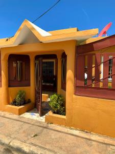 een klein geel huisje met een voordeur bij Tu Casa En Pedernales in Pedernales