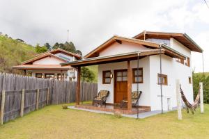 a small white house with a fence at Chalés Ninho do Poeta in Gonçalves
