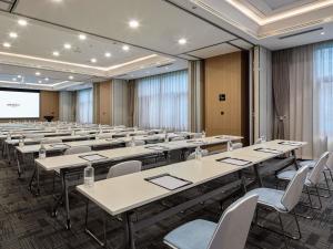una sala de conferencias con mesas y sillas y una pantalla de proyección en Mercure Xi'an Daming Palace, en Xi'an