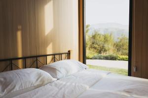 Una cama con almohadas blancas frente a una ventana. en Ninekm Forest Wilderness X by Tiny Away, en Wufeng