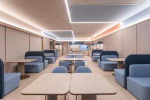 a waiting room with tables and blue chairs at Hanting Hotel Nanjing Hexi Wanda in Nanjing