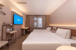 a hotel room with two beds and a flat screen tv at Hanting Hotel Nanjing Hexi Wanda in Nanjing +48 photos
