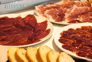 three plates of meat and bread on a table at Hotel La Alfonsina in Santibáñez de Villacarriedo