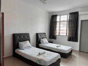 een slaapkamer met twee bedden en een raam bij Homestay 76 in Mersing