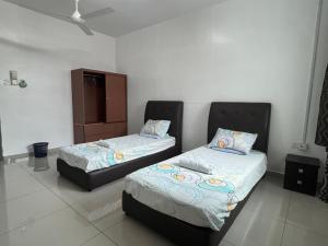 a bedroom with two beds and a cabinet in it at Homestay 76 in Mersing