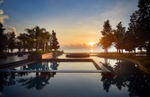 a swimming pool with a sunset in the background at Timurbay Residences in Kuantan