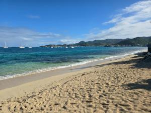 a sandy beach with boats in the water at Beach Front Apartment & Car Rental in Baie Nettle