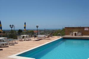 a swimming pool with chairs and tables on a building at Agriturismo Casale Di Gricciano in Cerveteri