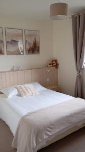 Chez Vivi et Jean Pierre Maison 8 à 9 personnes au calme vue montagne WIFI في جوراردُميه: غرفة نوم بسرير ابيض مع صور على الحائط